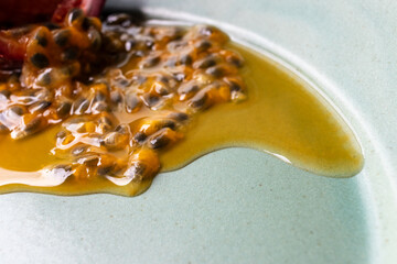 Fruit and juice spilling out of a halved passion fruit on a plate