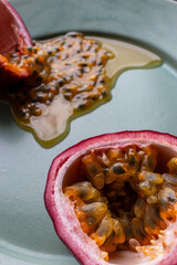 Fruit and juice spilling out of a halved passion fruit on a plate