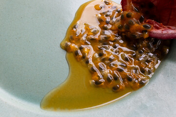 Fruit and juice spilling out of a halved passion fruit on a plate