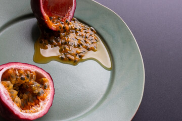 Fruit and juice spilling out of a halved passion fruit on a plate