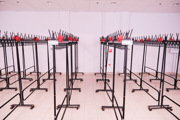 Empty coat racks with numbered tabs in a spacious white room. Public wardrobe area ready for an event or concert.
