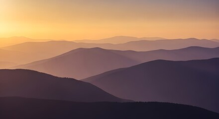 Layered mountain ranges silhouetted against a warm sunset sky with soft light and hazy atmosphere