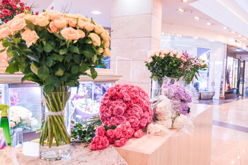 Large bouquets of pink, cream, and purple flowers on display in a flower shop or mall setting. Floral arrangement for gift.