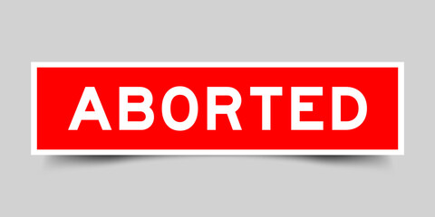 Red color square shape sticker label with word aborted on gray background