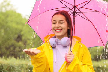Young woman with yellow raincoat and pink umbrella in park © Pixel-Shot
