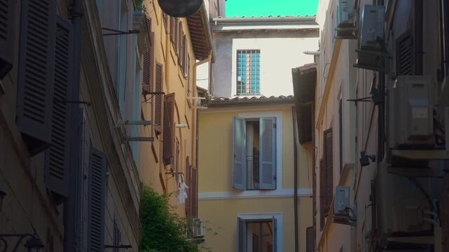 Narrow residential Roman alley with shuttered windows, air conditioning units, pastel walls, and open windows revealing authentic everyday Mediterranean neighborhood life
