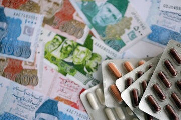 Pakistan rupees banknotes and medicine pills. Pakistan money bills with drugs close up