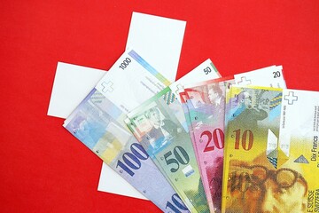 Swiss franc banknotes and flag. The current francs money bills lies on flag in big amount