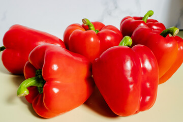 Fresh bright red bell peppers on olive background. Natural vegetables, healthy ingredients, vibrant food composition and culinary concept.