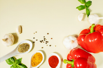 Spoons with spices, red bell peppers, garlic, basil and black peppercorns on olive background. Natural products, vegetables, culinary ingredients, food background for cooking and advertising.