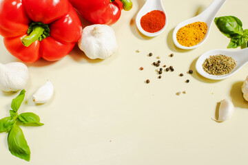 Spoons with spices, red bell peppers, garlic, basil and black peppercorns on olive background. Natural products, vegetables, culinary ingredients, food background for cooking and advertising.