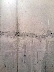 Texture of grey concrete wall with dark water and oil marks running vertically down
