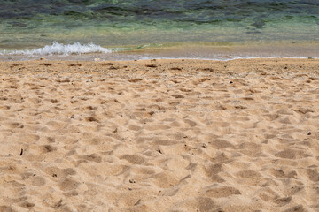 ​A peaceful shot of gentle waves lapping onto a sandy beach.