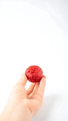 Hand holding a round red food item
