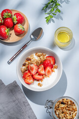 Granola or muesli with natural greek yogurt, strawberry and honey in a bowl on a blue background