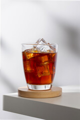 Iced americano in a glass on a white table in the cafe.