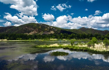 Aerial view of serene Lugu Lake surrounded by majestic mountains in Xichang, China - peaceful natural lakeside scenery with cloud reflections