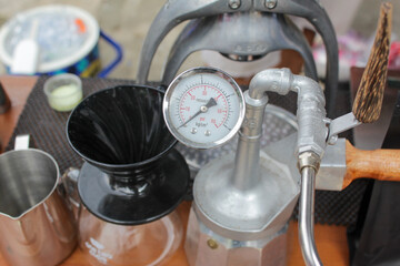 Close up of coffee brewing equipment with pressure gauge and pour over dripper