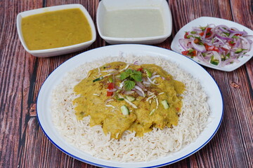 Dal Chawal with the bowl of dal, raita and salad on a wooden background
