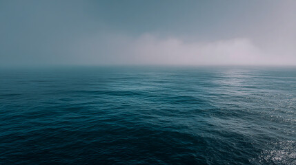 Obraz premium Misty ocean horizon with blue and gray water under a calm sky, tranquil seascape, soft atmospheric lighting, high-resolution.