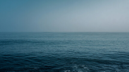 Obraz premium Misty ocean horizon with blue and gray water under a calm sky, tranquil seascape, soft atmospheric lighting, high-resolution.