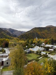 Peaceful Mountain Village in Autumn Valley with Colorful Fall Foliage and Dramatic Sky