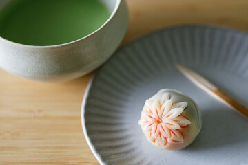 Cup of fresh matcha tea, green tea and Nerikiri, Japanese confectionery, on wooden table.