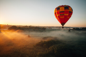 Obraz premium Hot air balloon flying over foggy landscape at sunrise