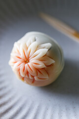 A piece of delicious Japanese confectionery on off white ceramic plate on wooden table.
