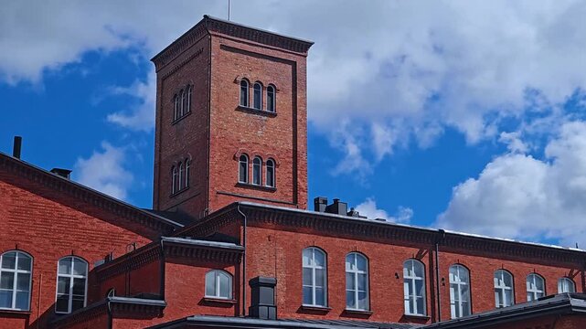 Old industrial red brick victorian architecture building with windows, tower and nice decorative details. 