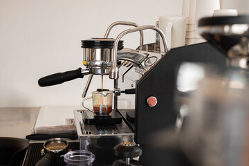 Professional espresso machine brewing fresh coffee shot into a glass measuring cup in modern café. Close-up of barista equipment for quality coffee preparation and caffeine concept.