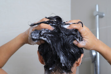 A woman washes her hair and takes a shower in the bathroom.