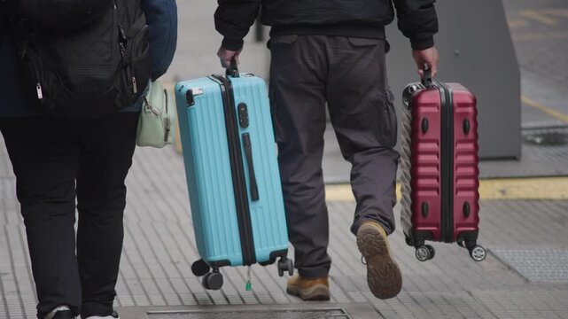 Tourists walking with suitcases along a busy street in downtown Buenos Aires. Urban travel scene with people carrying luggage in a vibrant city center, capturing the atmosphere of tourism, movement, a