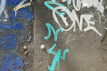 Macro shot of weathered graffiti strokes in blue and white paint on rough gray concrete surface, abstract textures and layered details