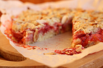 Freshly baked strawberry almond crumble pie with crunchy topping on parchment paper. Juicy berry filling, golden crust, rustic style, blurred background for food photography