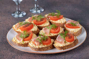 Bruschetta with bacon and tomatoes on rye bread toast on white plate