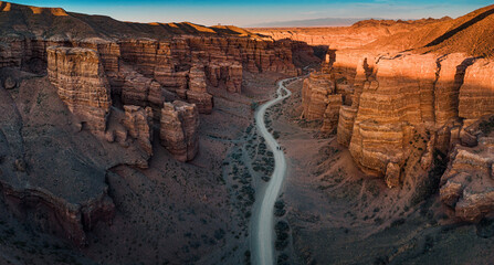 Winding road crossing Charyn Canyon in Kazakhstan, illuminated by the warm light of the setting sun