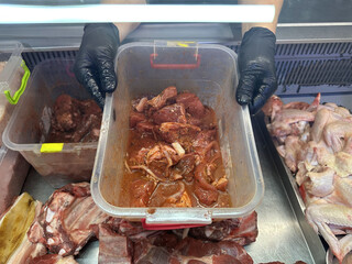 hands hold tray of pork meat in tomato juice