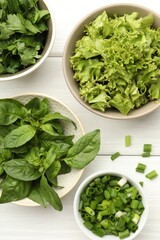 Different aromatic herbs in bowls on white wooden table, flat lay