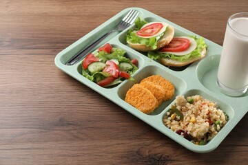 Plastic tray with tasty food, milk and fork on wooden table, closeup. School lunch