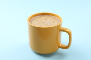 Aromatic coffee in cup on light blue background, closeup