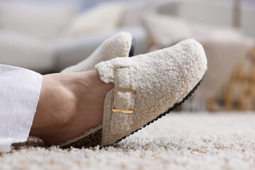 Woman in stylish slippers on soft carpet at home, closeup