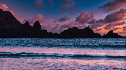 Dramatic sunset over the ocean in Devon UK with silhouetted rocks. Serene and peaceful.