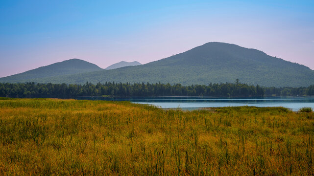 Early autumn landscape over Flagstaff Lake and marshland in Maine with water reflections of the mountains, tranquil beauty in the heart of New England’s seasonal transition.