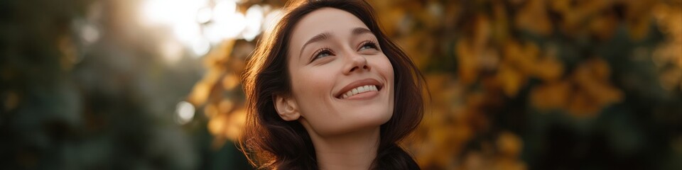 Fototapeta premium Caucasian young female smiling in autumn sunlight amidst fall foliage