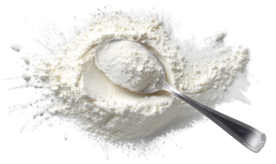 Flour spills around a metal spoon filled with flour