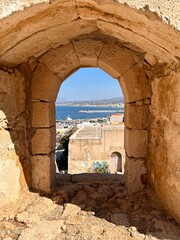 Scenic view through stone window in the old fortress walls of Rethymno, Crete, Greece
