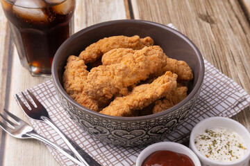 Breaded chicken bites in a bowl over wooden table