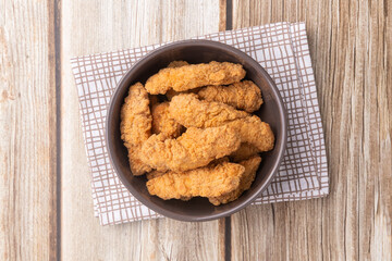 Breaded chicken bites in a bowl over wooden table