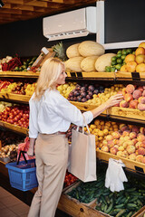 Blonde woman selects fresh organic fruits in a vibrant grocery store market setting